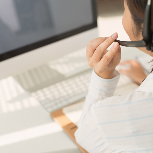 Frau mit Headset sitzt vor einem PC.