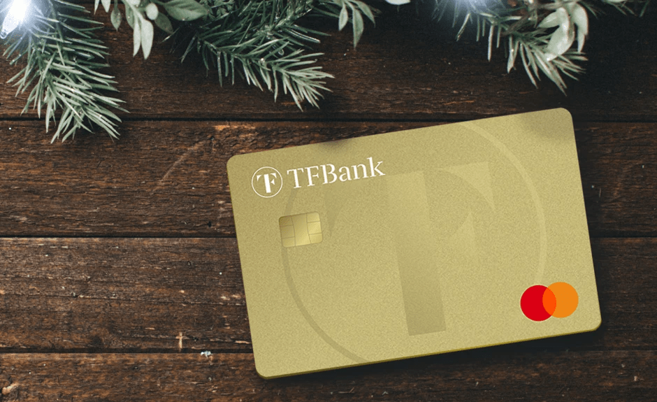 Tf Mastercard Gold liegt auf einem braunen Tisch. Im HIntergrund ist ein Tannenzweig zu sehen.