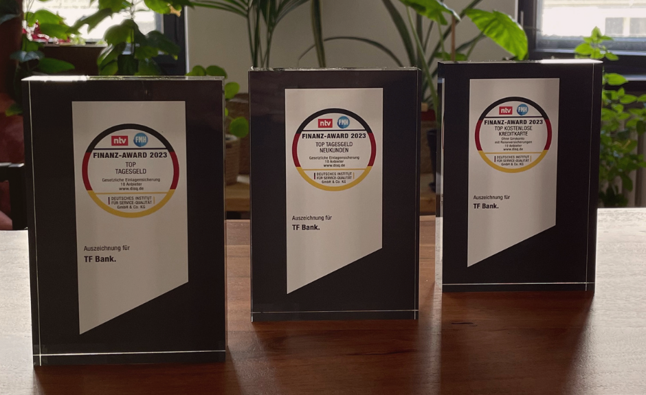3 Awards der TF Bank aus dem Jahr 2023 stehen auf dem Tisch. Auszeichnungen zur Kreditkarte sowie Geldanlagen