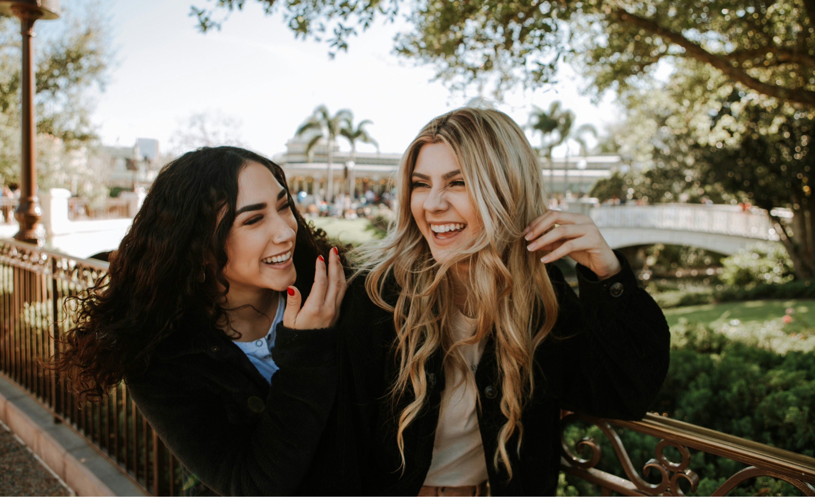 Zwei Freundinnen laufen dicht Arm in Arm und lachen.