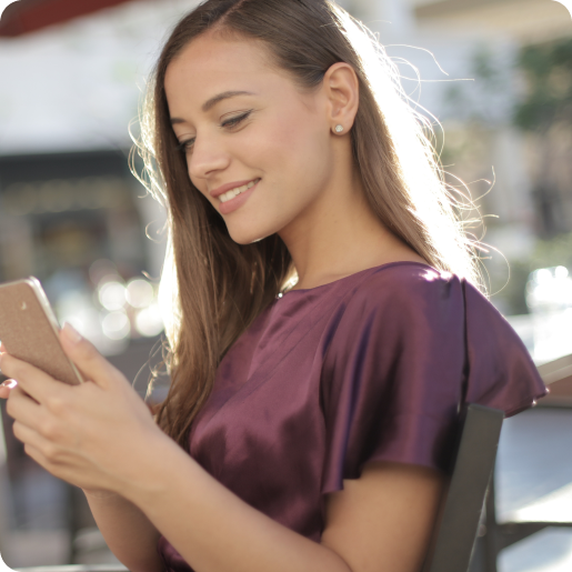 Frau schaut lächelnd auf ihr Handy.