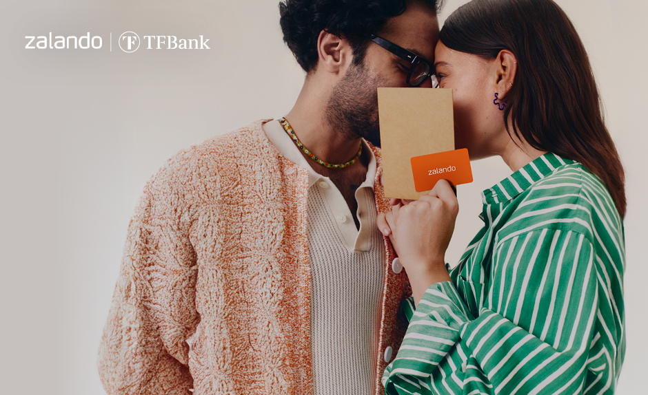Zalando Gutschein: Paar schaut sich verliebt an, hält den Zalando Gutschein vor dem Gesicht