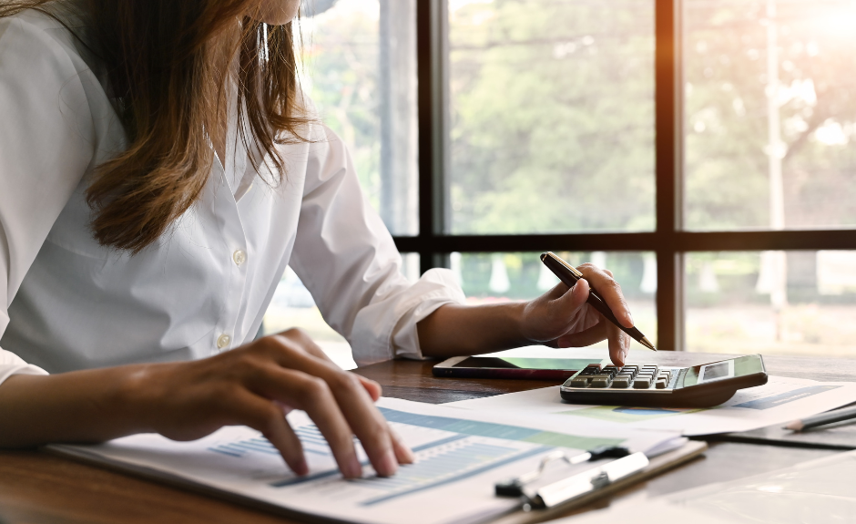 Frau sitzt am Tisch und kalkuliert Finanzen